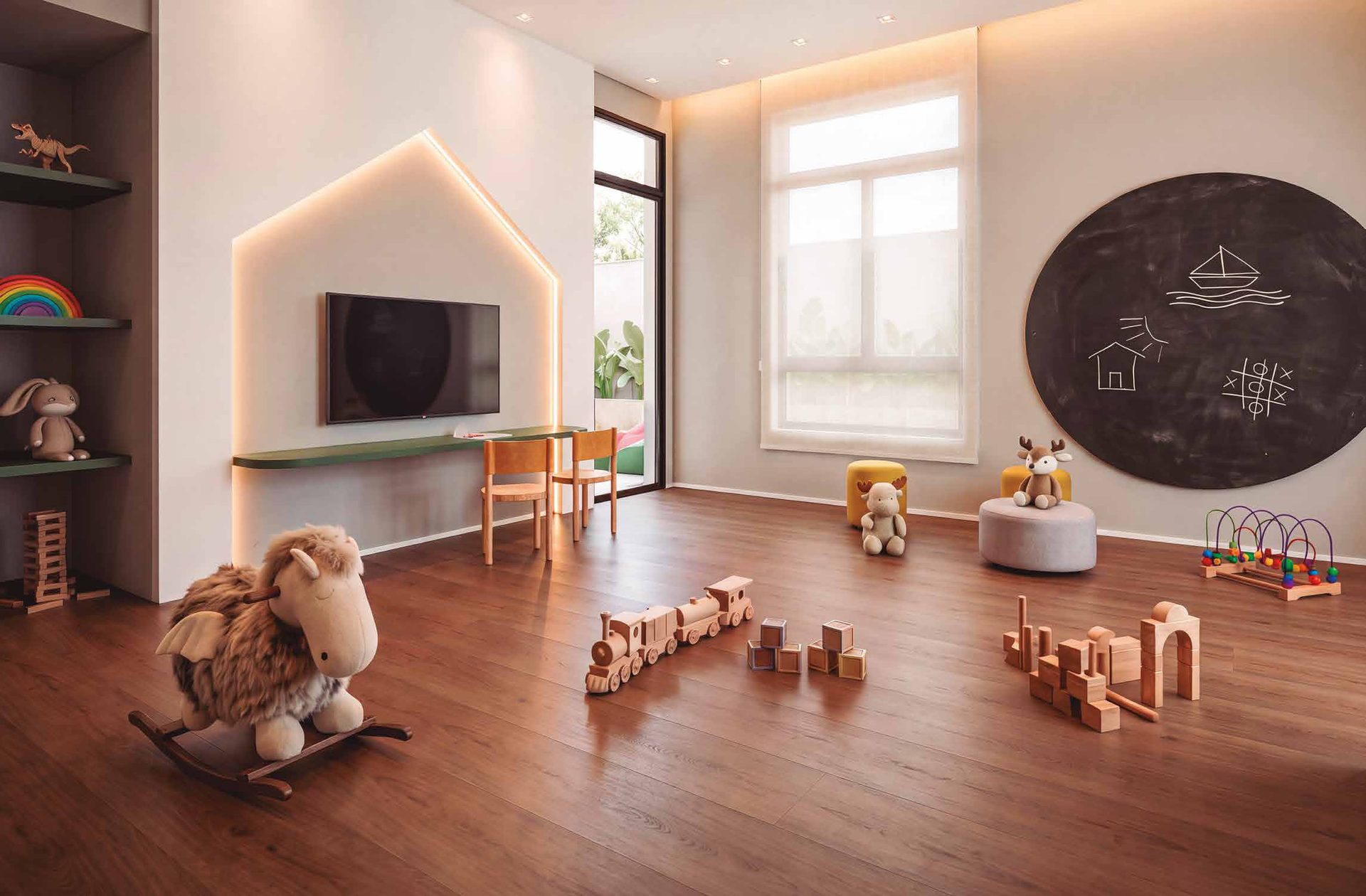 Brinquedoteca do Elysium, com painel de lousa, TV e brinquedos de madeira